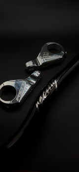 Close-up of chrome Riot Racing stem components beside a black Riot Racing handlebar.