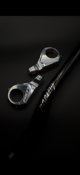 Two chrome Riot Racing stem components arranged beside a black handlebar on a dark background.